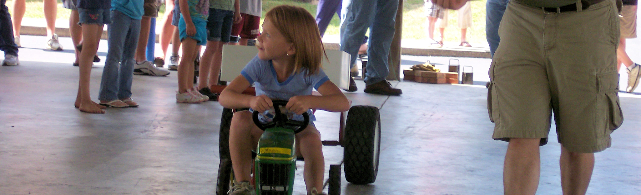 Photo of a young girl on a small toy tractor
